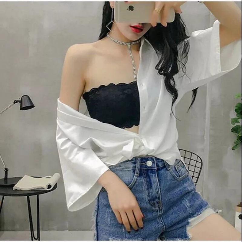 alt text: Cô gái mặc áo bra thể thao màu xám bên trong áo sơ mi trắng oversized, kết hợp với quần short jeans và giày thể thao, tạo nên vẻ ngoài năng động, khỏe khoắn.