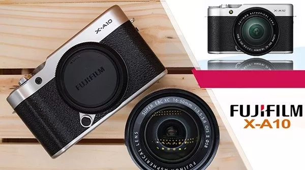 alt text: Máy ảnh Fujifilm X-A10 màu bạc, ống kính đen, đặt trên bàn gỗ